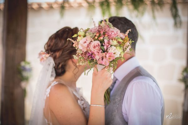 Novios besándose tras el ramo de la novia