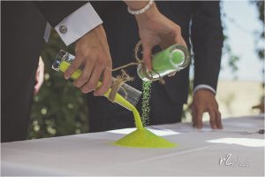 Novios durante ceremonia civil mediante el rito de la arena con arena colores verde y amarilla