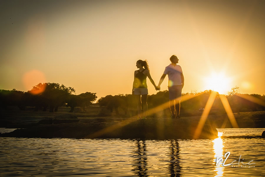 Novios de la mano a la puesta de sol frente a una charca durante sesión de preboda en Arroyo de la Luz (Cáceres) Boda A&P