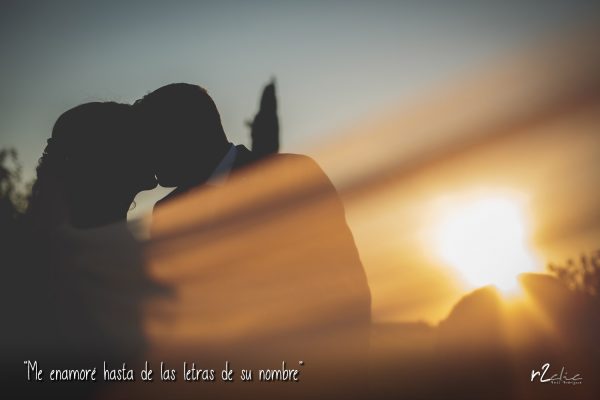 “Me enamoré hasta de las letras de su nombre” (Reportaje de boda en el hotel “Hospes Palacio de Arenales” (Cáceres) Foto de r2clic.com, tomada durante un reportaje de boda en el. “Palacio de Arenales” (Cáceres). Contraluz de novios besándose al atardecer en el Palacio de Arenales. Frase acompañando a foto: “Me enamoré hasta de las letras de su nombre” (Reportaje de boda en el hotel “Hospes Palacio de Arenales” (Cáceres)