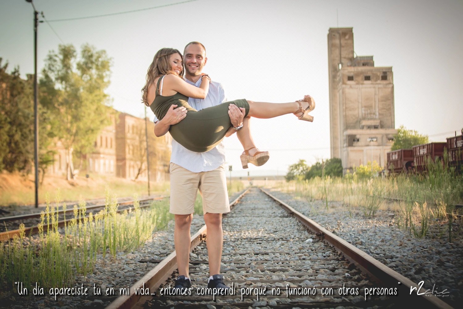 Foto 1039 de r2clic.com - Proyecto 365VecesTeQuiero (Fotos de boda y frases de amor) - Reportaje de pre boda en la estación de tren De Arroyo de la luz. Novio cogiendo en brazos a la novia en medio de unas vidas de tren. Frase acompañando a foto: “Un día apareciste tu en mi vida… entonces comprendí porqué no funcionó con otras personas” (Reportaje de preboda en Arroyo de la Luz)