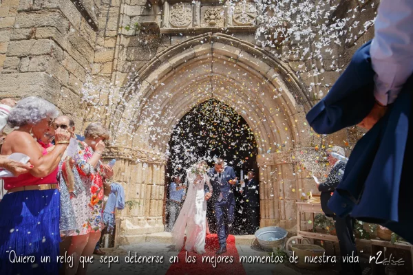 Foto 1245de r2clic.com - Proyecto 365VecesTeQuiero (Fotos de boda y frases de amor) - Reportaje de boda en Navas del Madroño. Novios bajo la lluvia de pétalos al finalizar la ceremonia religiosa en la iglesia Ntra. Sra de la O. Frase acompañando a foto: “Quiero un reloj que sepa detenerse en los mejores momentos de nuestra vida” (Reportaje de boda en Navas del Madroño - Ntra. Sra. de la O)