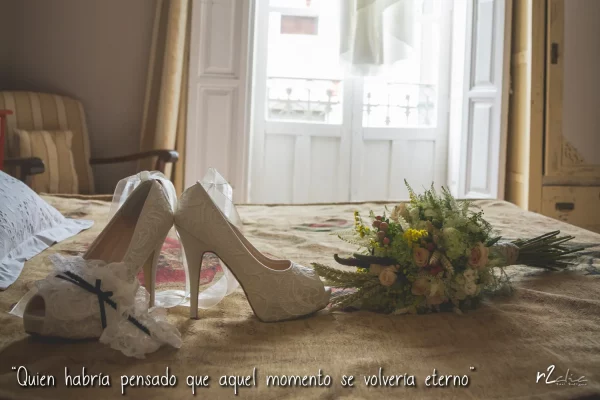 Foto 1272 de r2clic.com - Proyecto 365VecesTeQuiero (Fotos de boda y frases de amor) · Preparativos de la novia en Extremadura. Zapatos, ramo y liga sobre la cama con el vestido colgado al fondo. Frase acompañando a foto: “Quien habría pensado que aquel momento se volvería eterno” (Reportaje de boda en Extremadura)